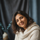 Close-up portrait of a happy South Asian woman in her late 30s, smiling peacefully and looking relaxed.